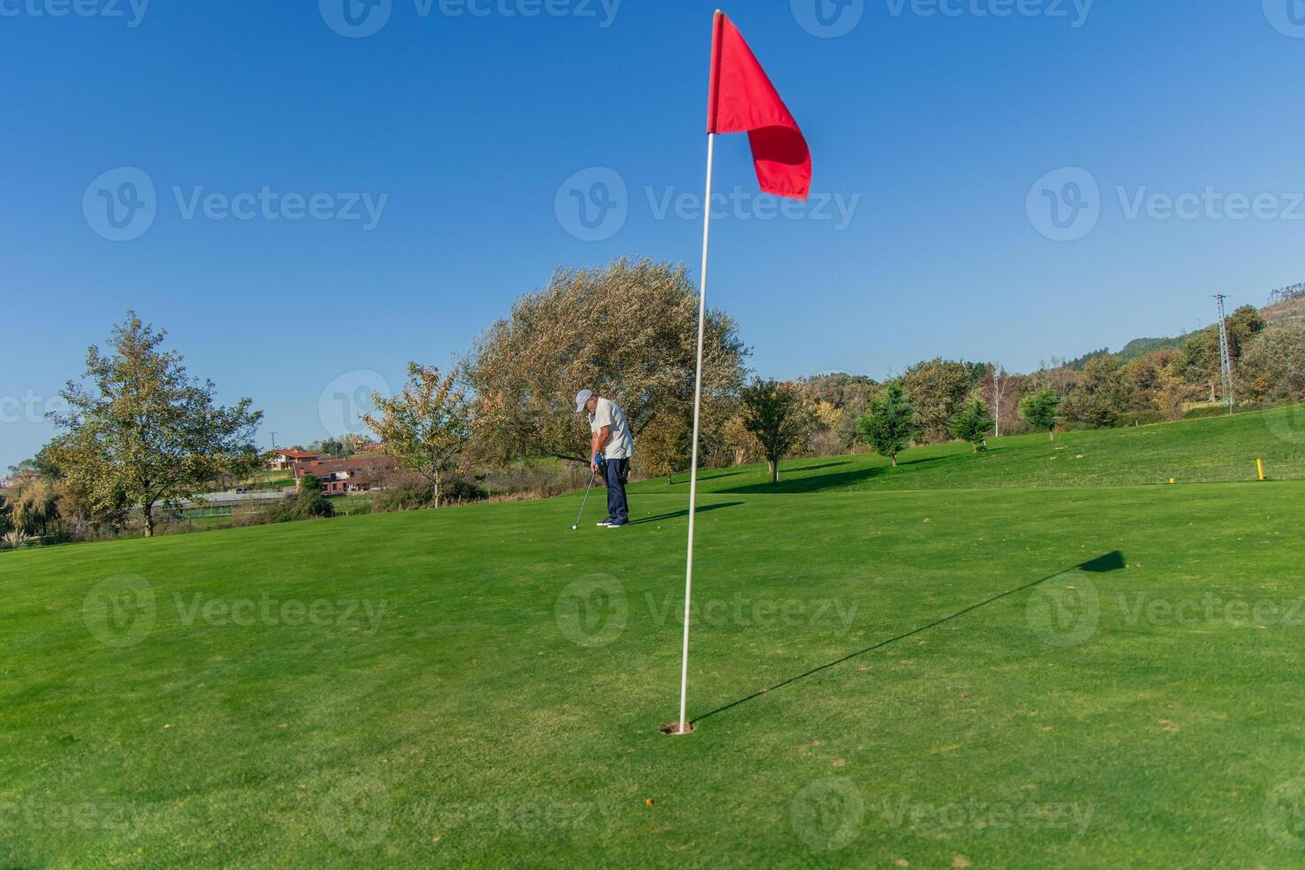 copyspace senior golfer putting ball toward flag on the green photo