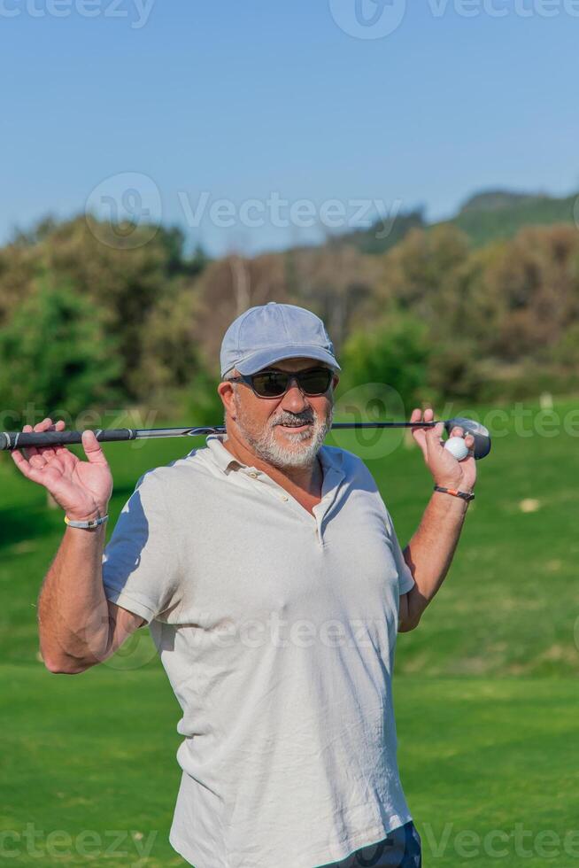 vertical senior golfer with cap and sunglasses smiling with golf club on shoulders photo