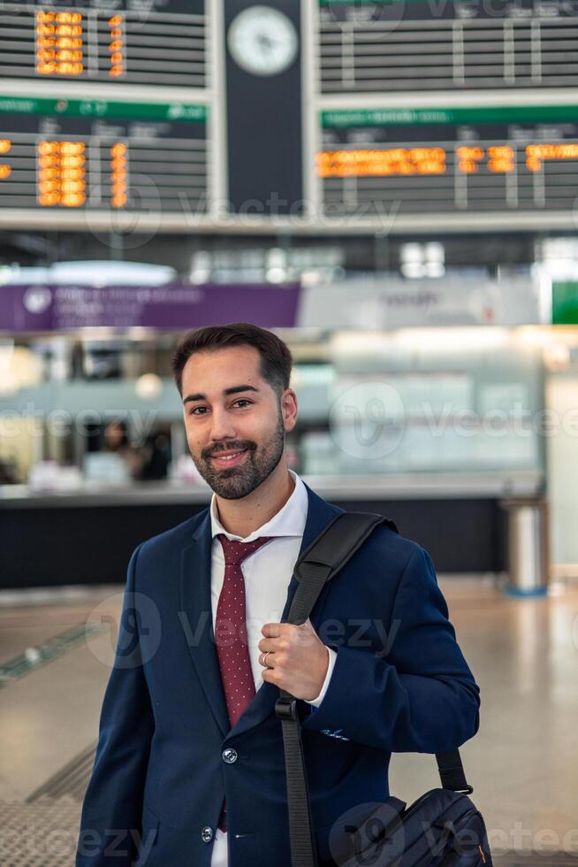 vertical Smiling businessman poses in train station on his way to work using public transport photo