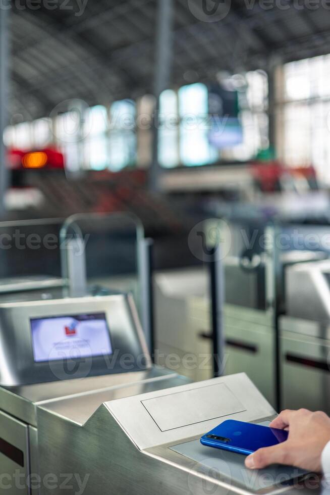 commuter's hand using contactless mobile payment at train barriers heading to financial district photo