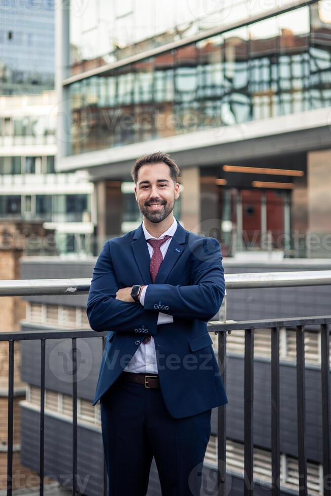 Businessman smiling with folded arms in urban setting photo