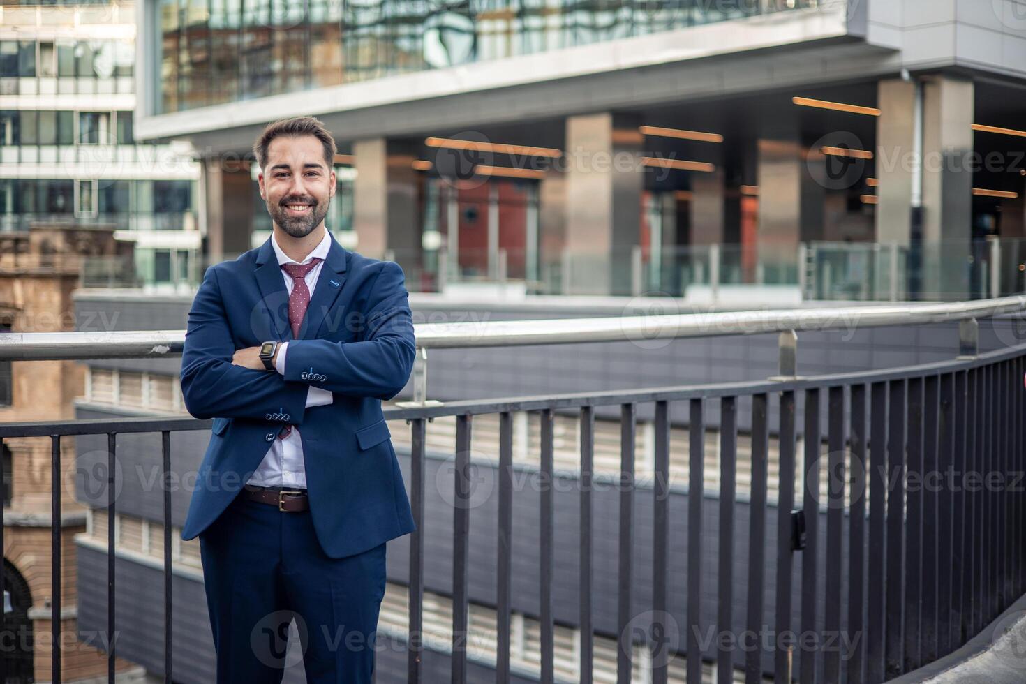 Smiling businessman posing with folded arms in urban setting photo