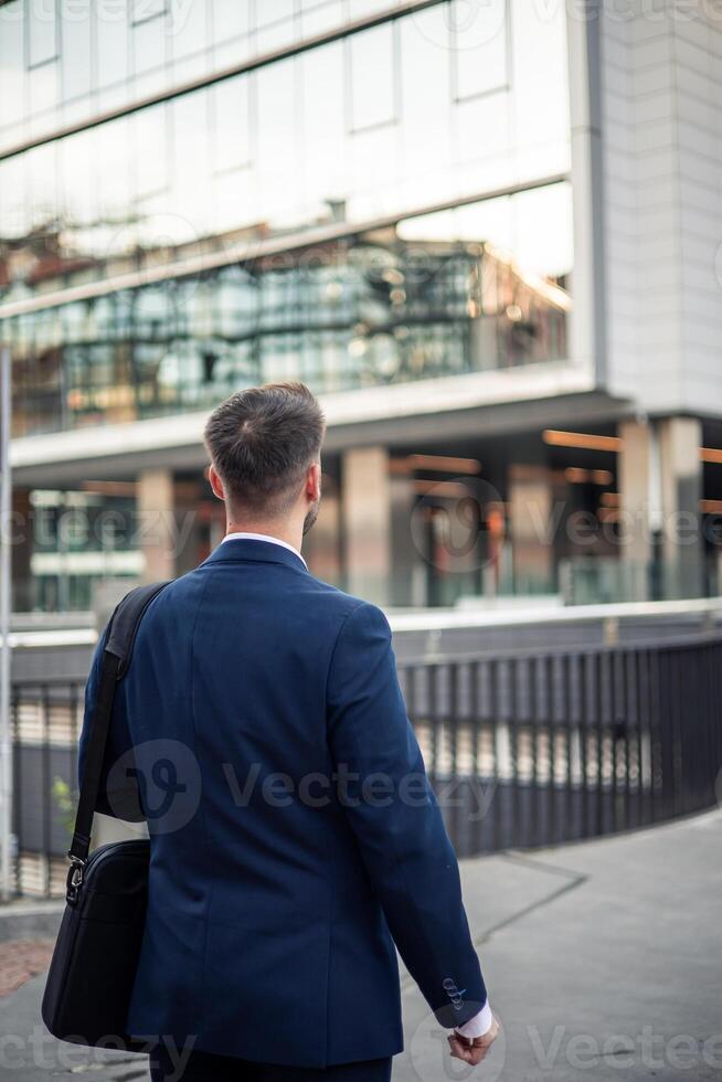 Businessman walking near office building looking around photo
