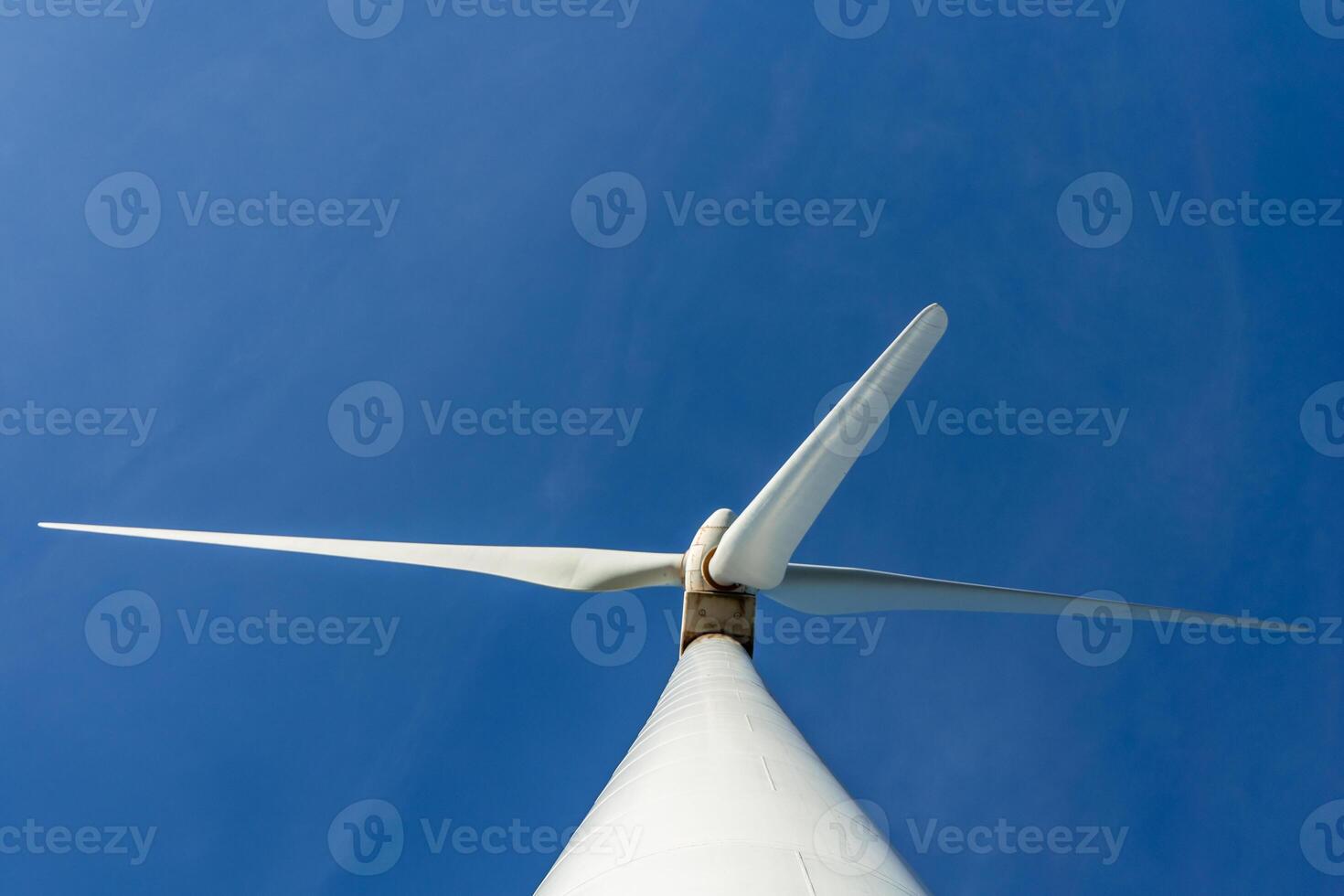 Wind turbine generating green energy against blue sky photo