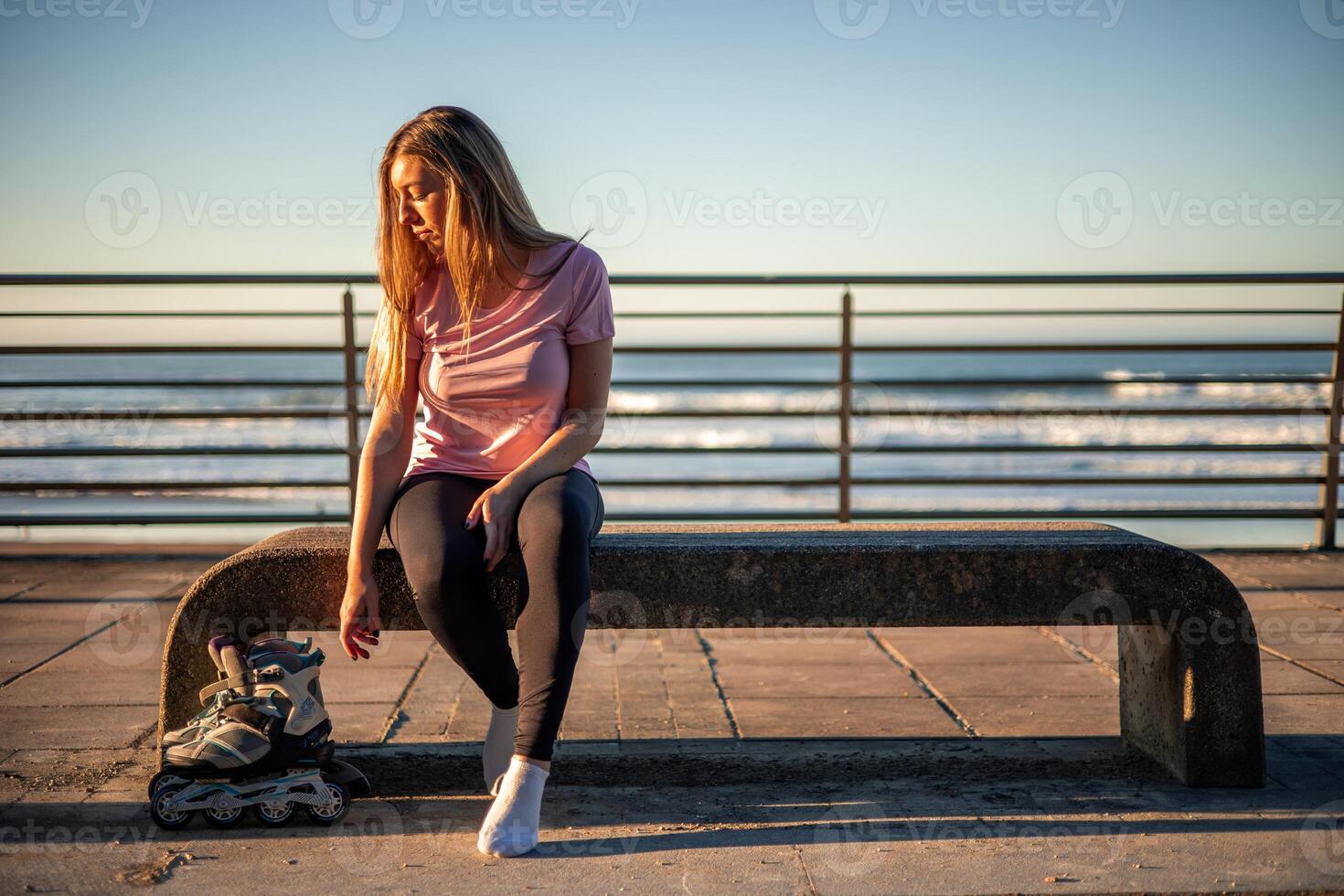 Young woman resting on a bench after inline skating by the sea copyspace photo