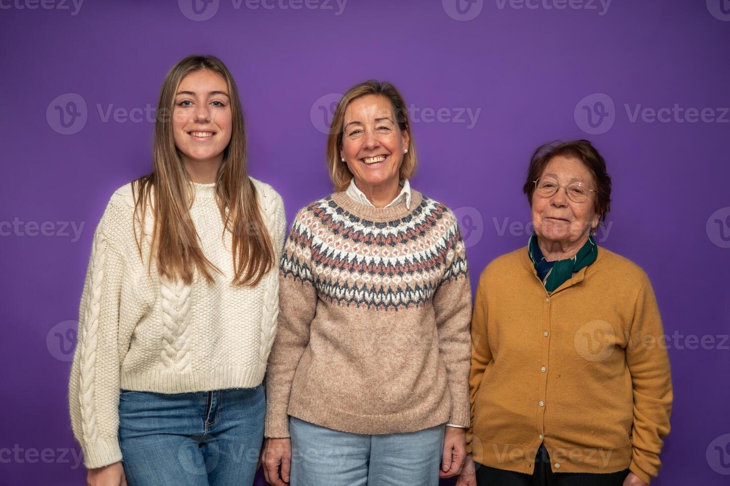 Three generations of women smiling and posing together on purple background photo