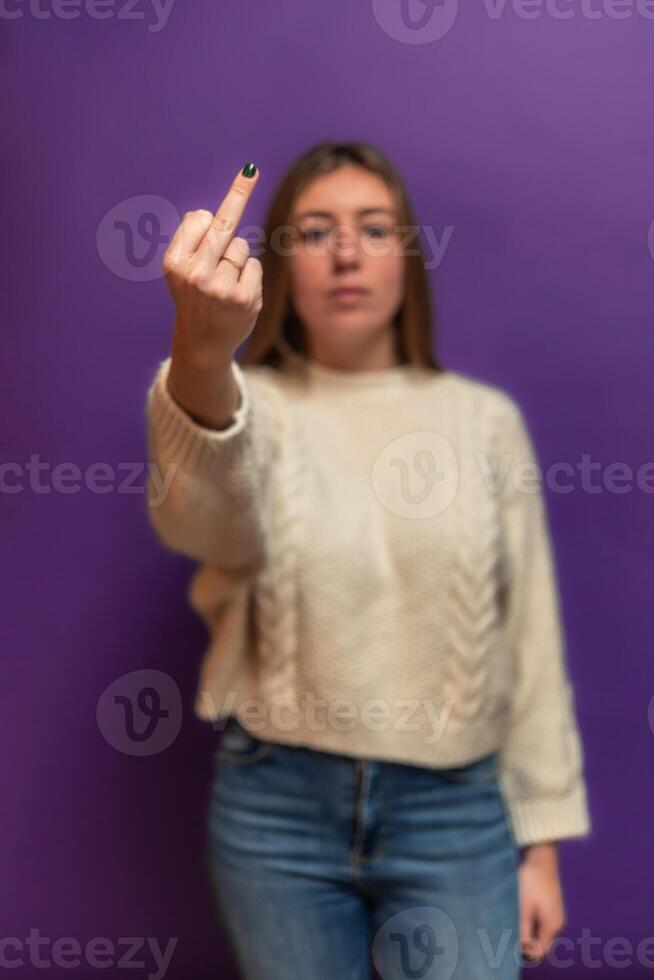vertical Young woman showing middle finger on purple background photo