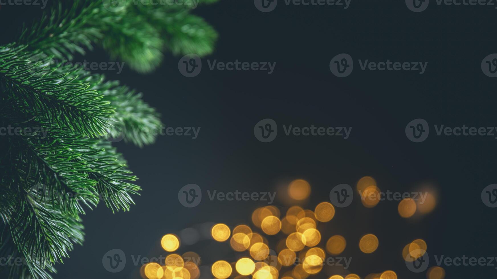 Christmas tree branch framing golden bokeh lights on a dark background creates a festive and magical holiday atmosphere, perfect for greeting cards or website banners photo