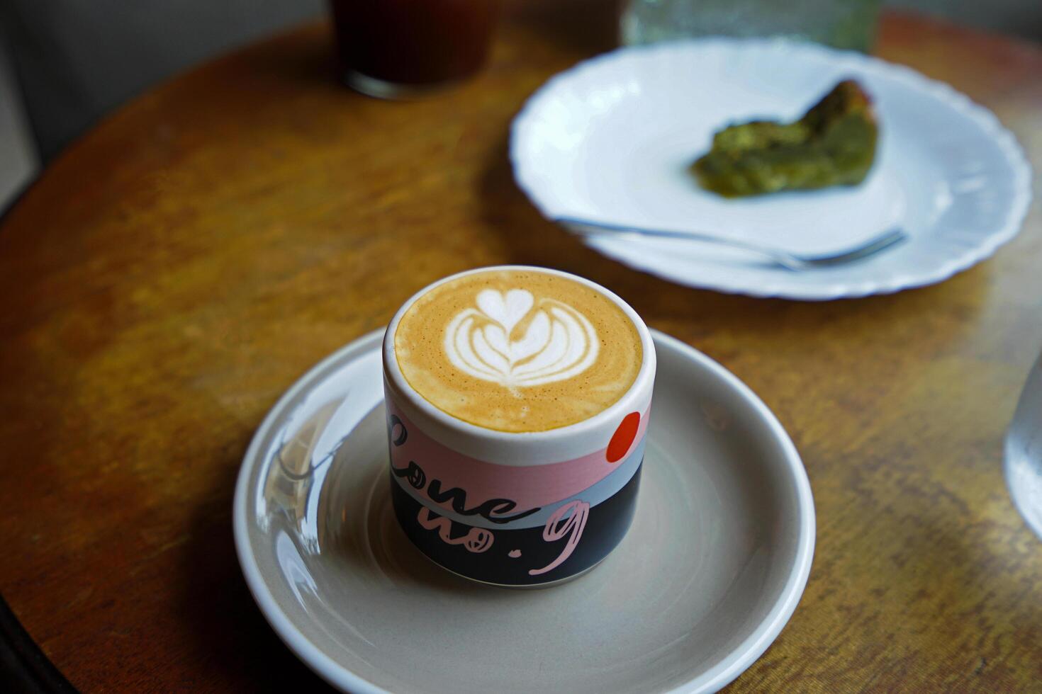 Close up ceramic mug of hot Latte and Matcha green tea cake on wooden table photo