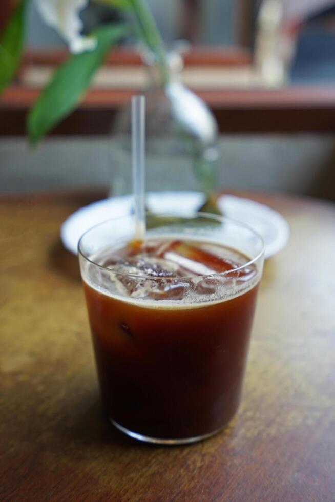 Close up glass of iced black coffee on wooden table photo