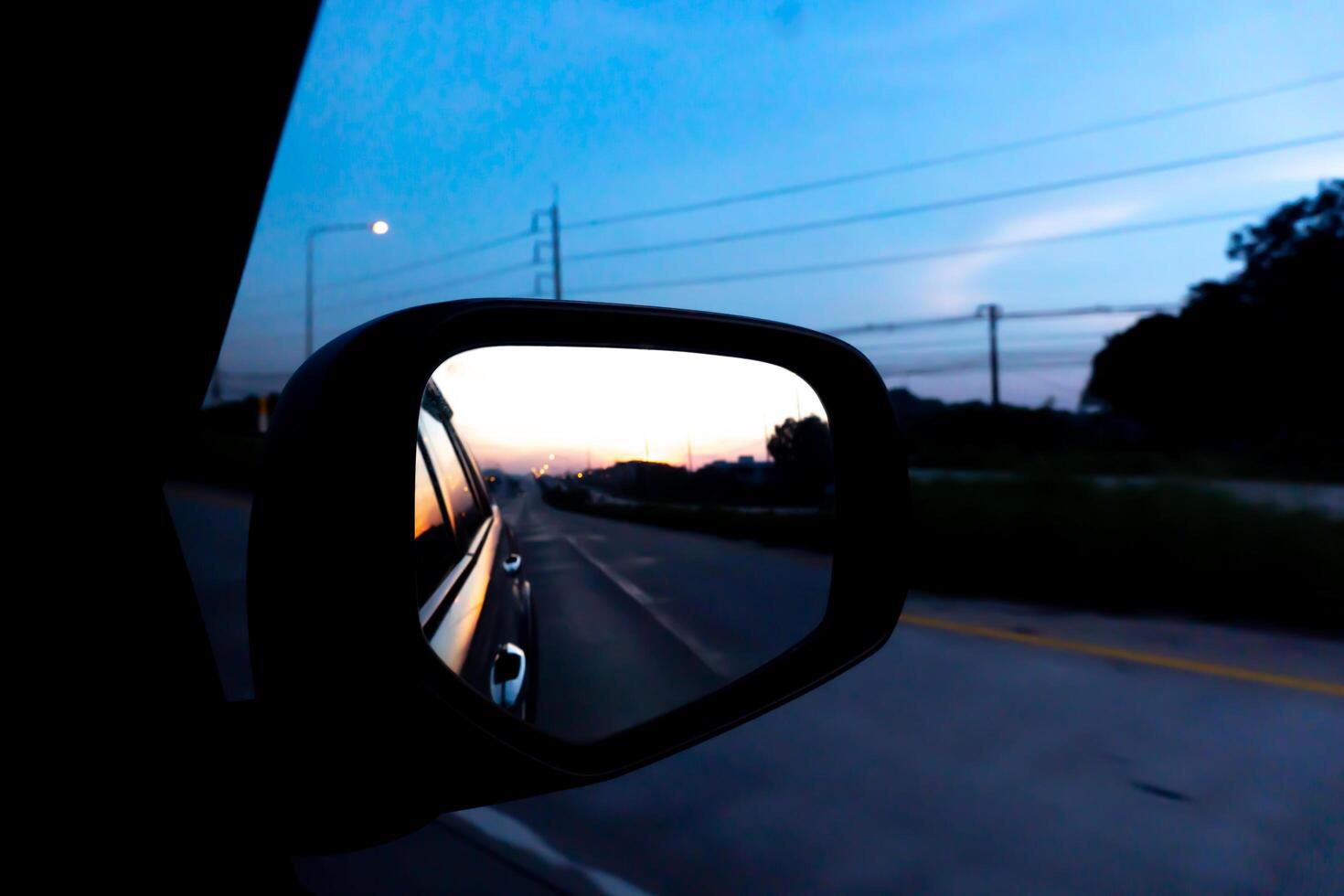 Reflection in the side mirror of a car during sunset. Blurred background photo