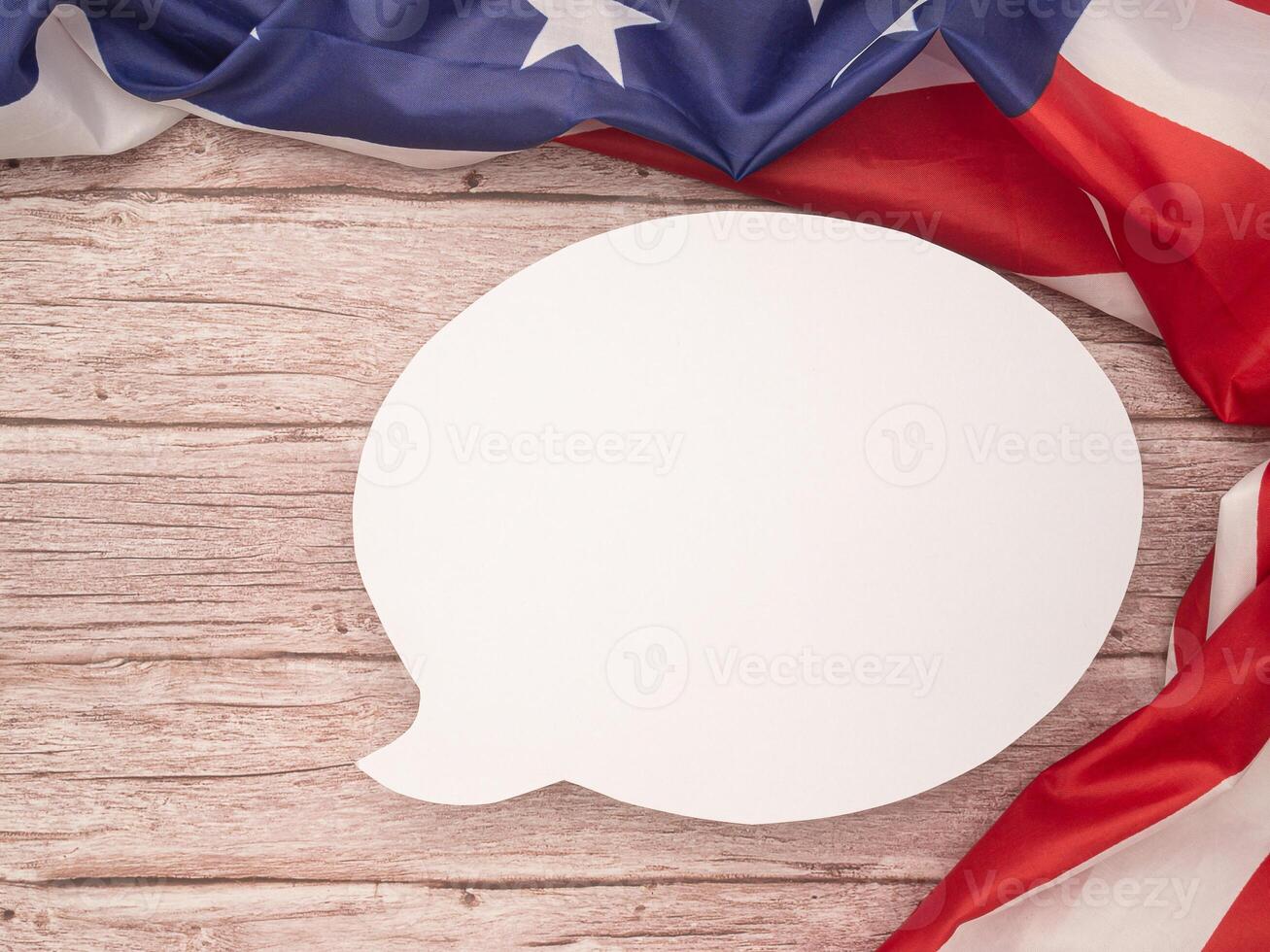 Top view of the American flag with a blank white speech bubble over a wooden table photo