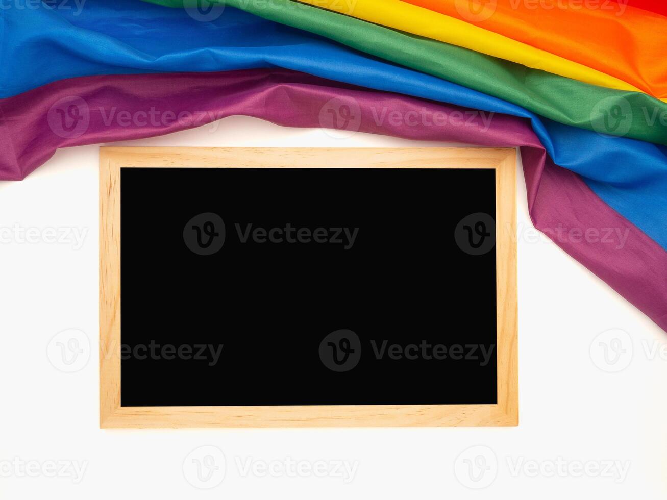 Top view of the rainbow flag or LGBT and a blank mini chalkboard with the wooden border over a white background photo