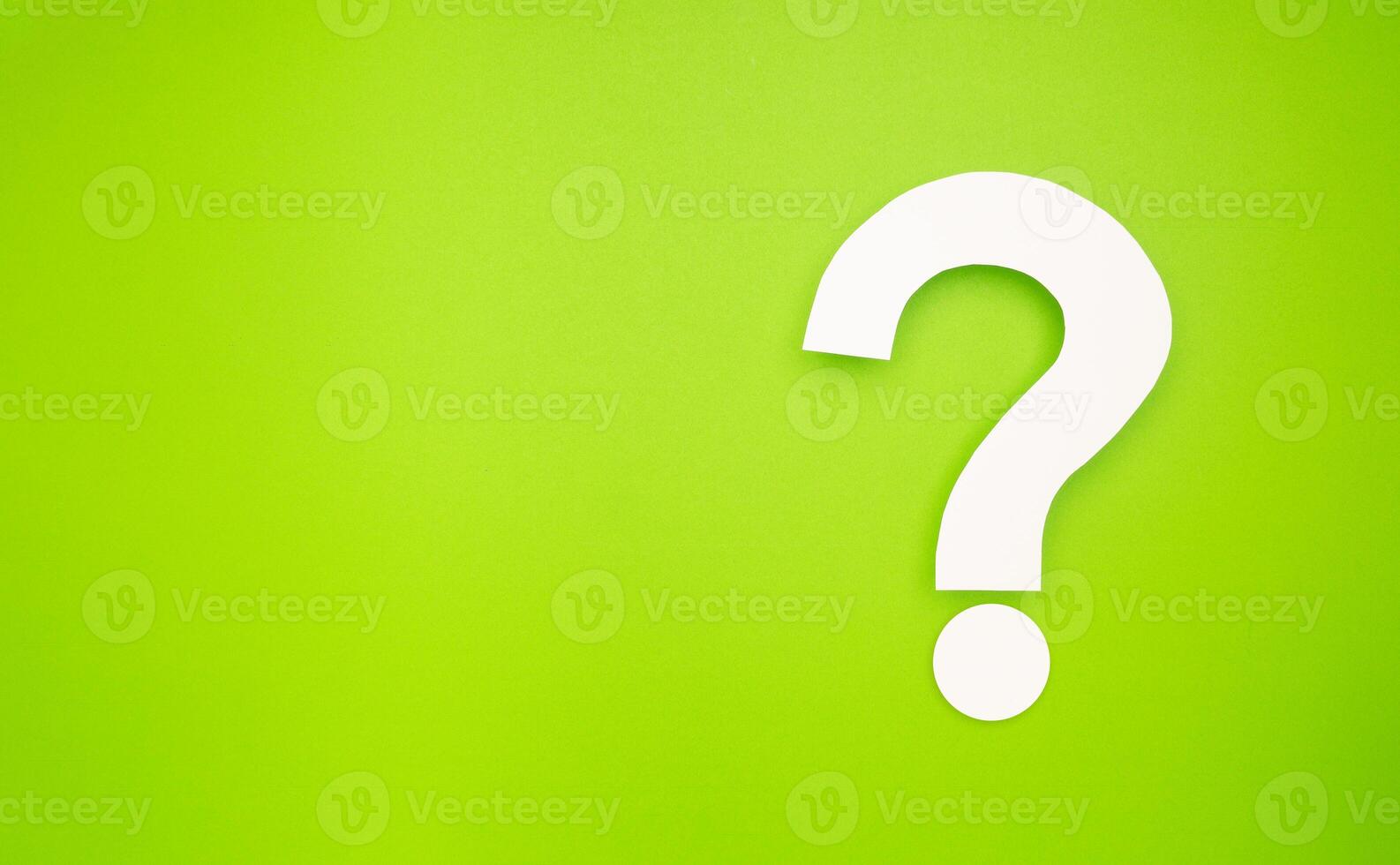 A question mark symbol is on a light green background photo