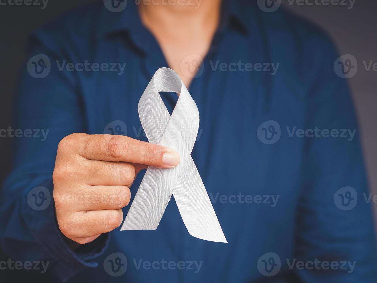 Close-up of hand holding a white ribbon on a gray background photo