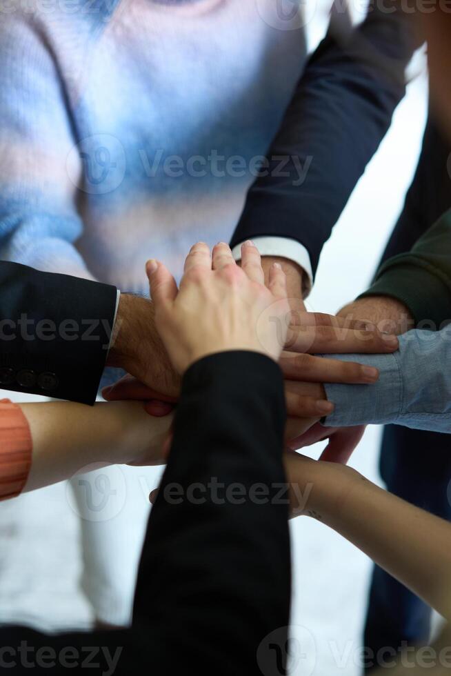 A top view of business people joining hands in a circle, symbolizing unity, collaboration, and shared success in the workplace photo