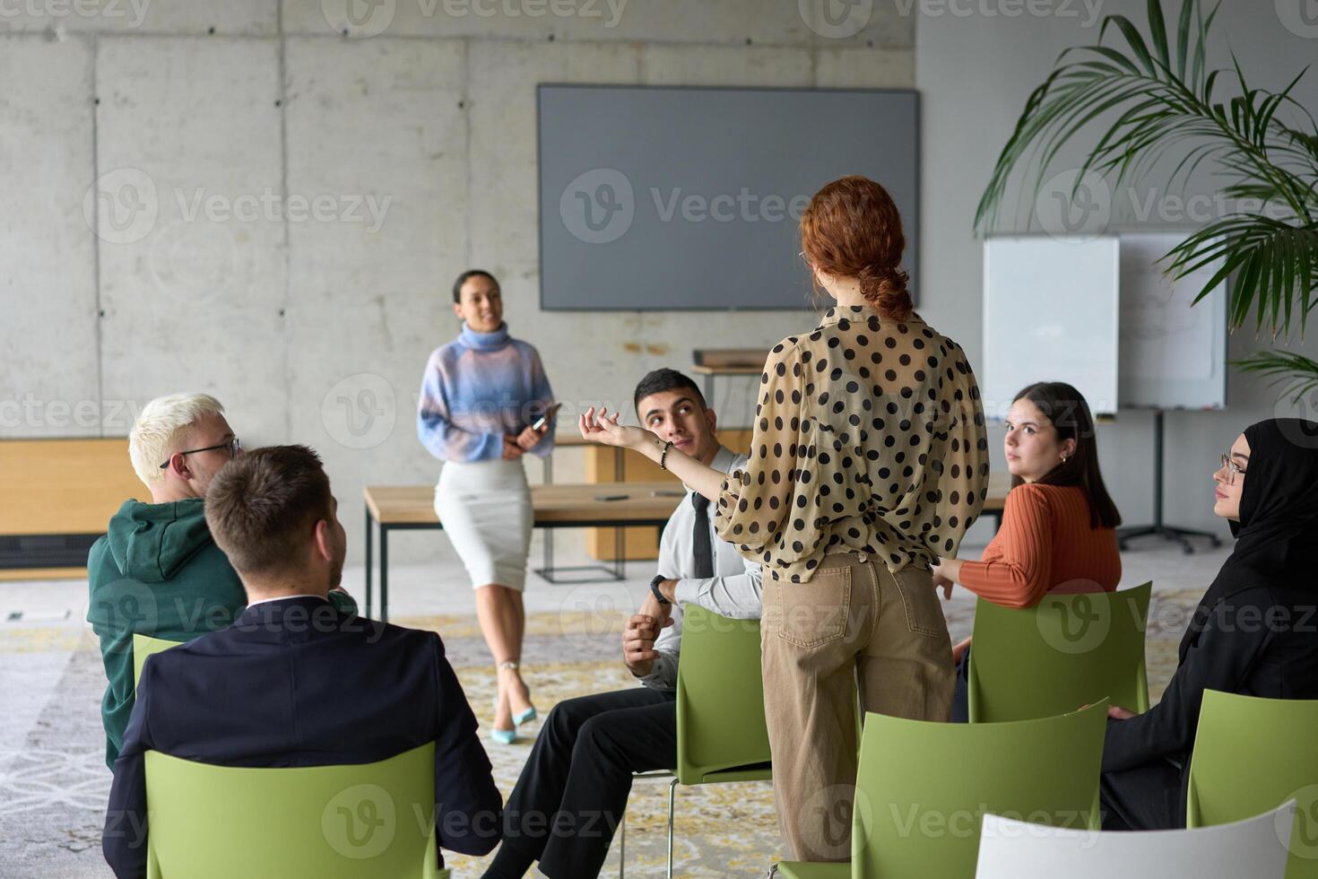 A diverse group of business professionals sits attentively in a modern office, actively participating in a training session led by an instructor, focusing on the latest technological advancements in photo