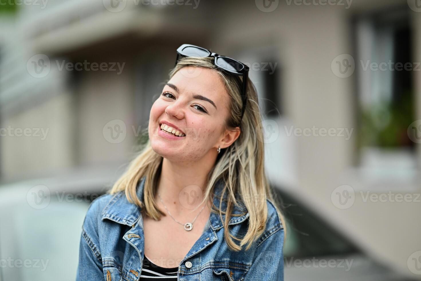 A radiant blonde woman with a wide, joyful smile showcasing her white teeth, enjoying a carefree moment in the beauty of nature. photo