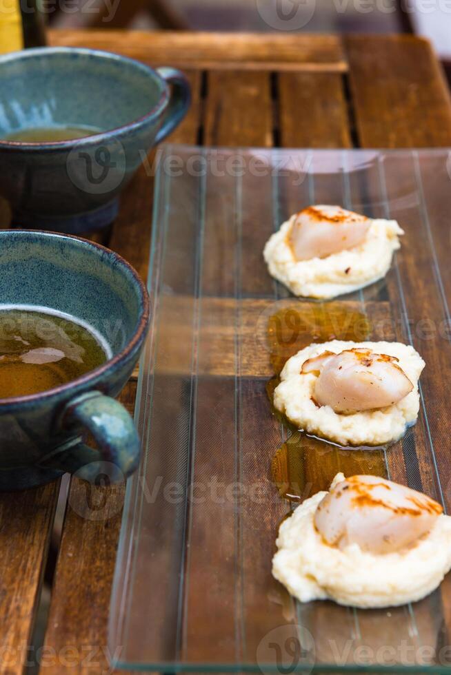 Close up of pan seared sea scallops and a cup of cider photo