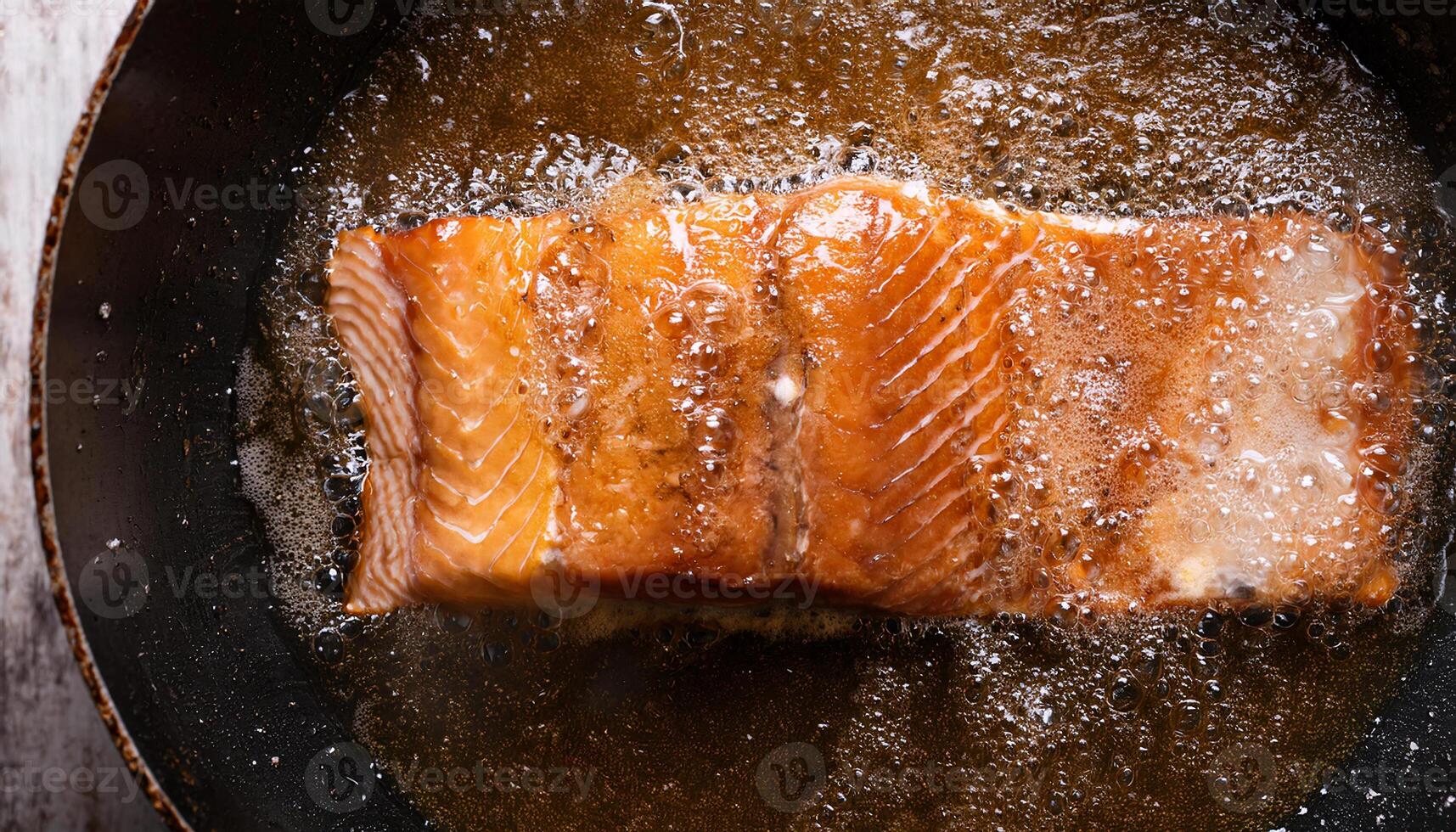 fillet of fresh salmon sizzling in bubbling oil with golden crispy textures forming during frying process photo