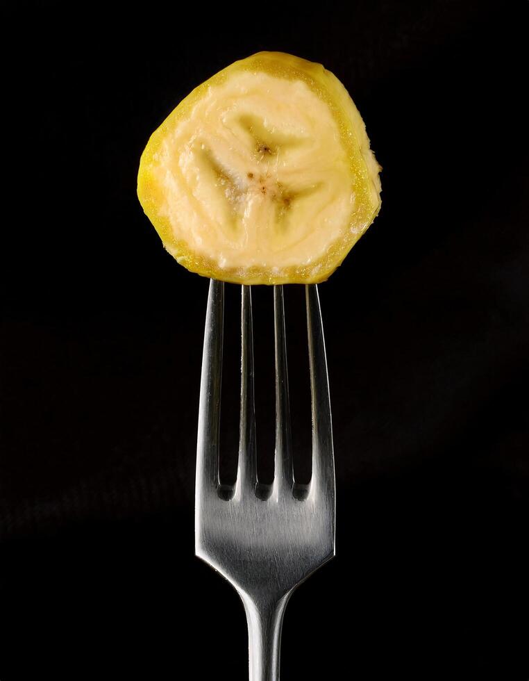close-up of a juicy banana slice on a sleek silver fork with black textured background high-resolution minimalistic food photography healthy snack concept for culinary and creative projects photo