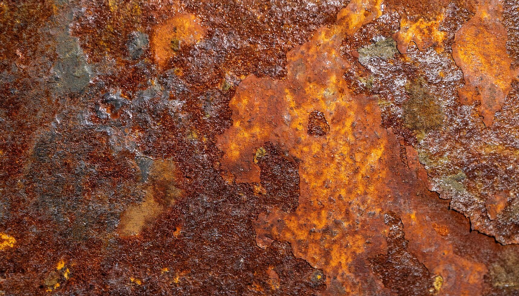 macro view of rusted steel surface with peeling layers and vibrant orange and brown corrosion patterns photo