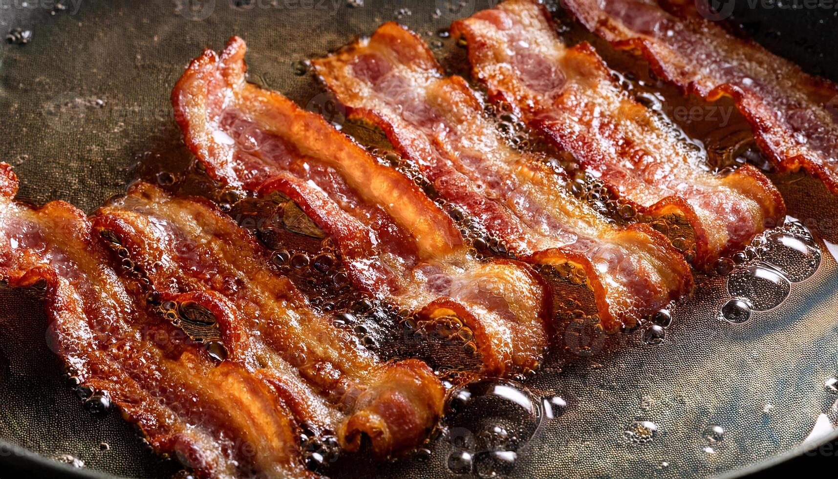 crispy bacon slices frying in hot oil with sizzling bubbles and curling edges for a delicious texture photo