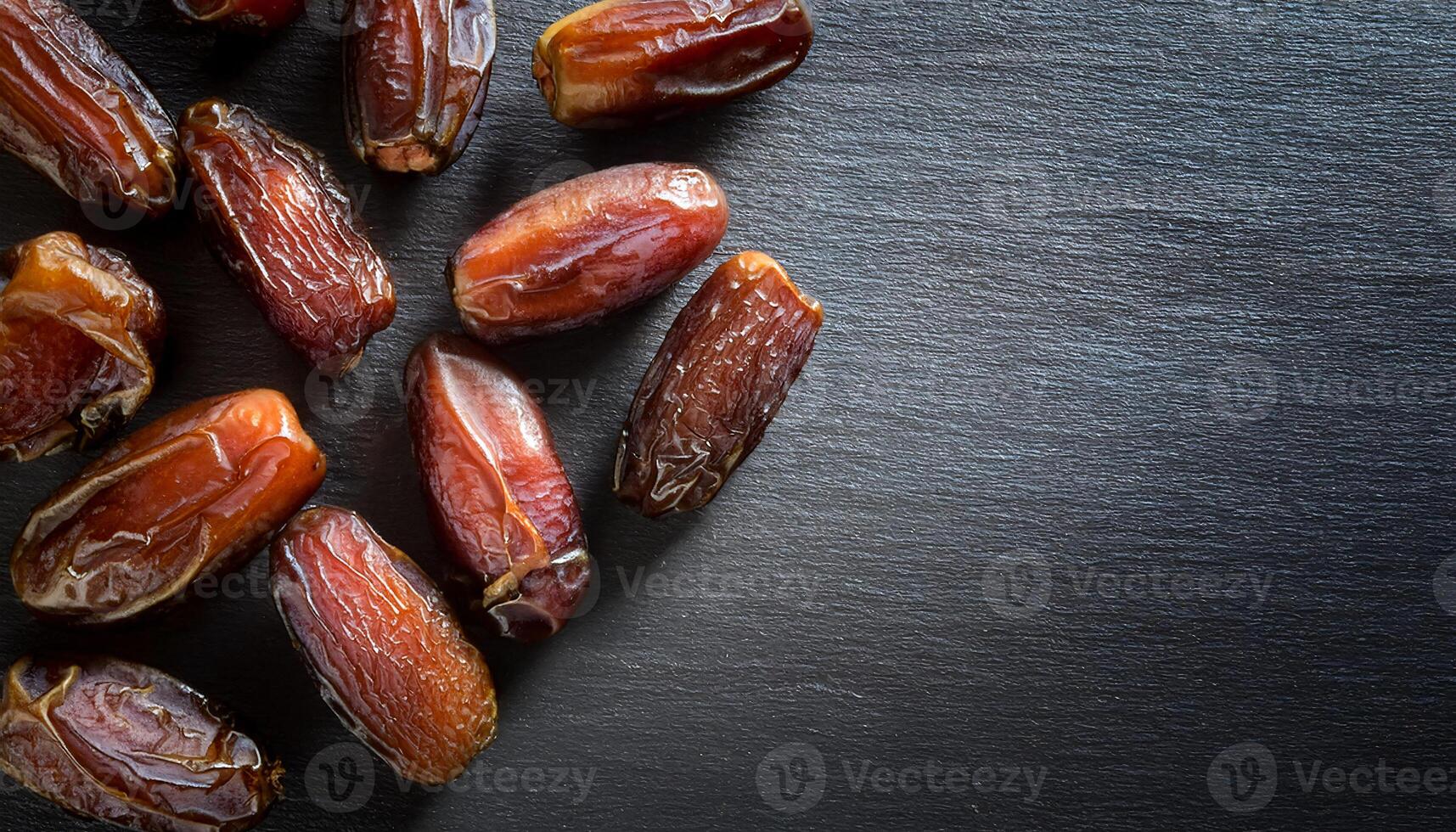 close-up of shiny dried dates on dark slate background with copy space for text or design, healthy and natural sweet snack concept photo