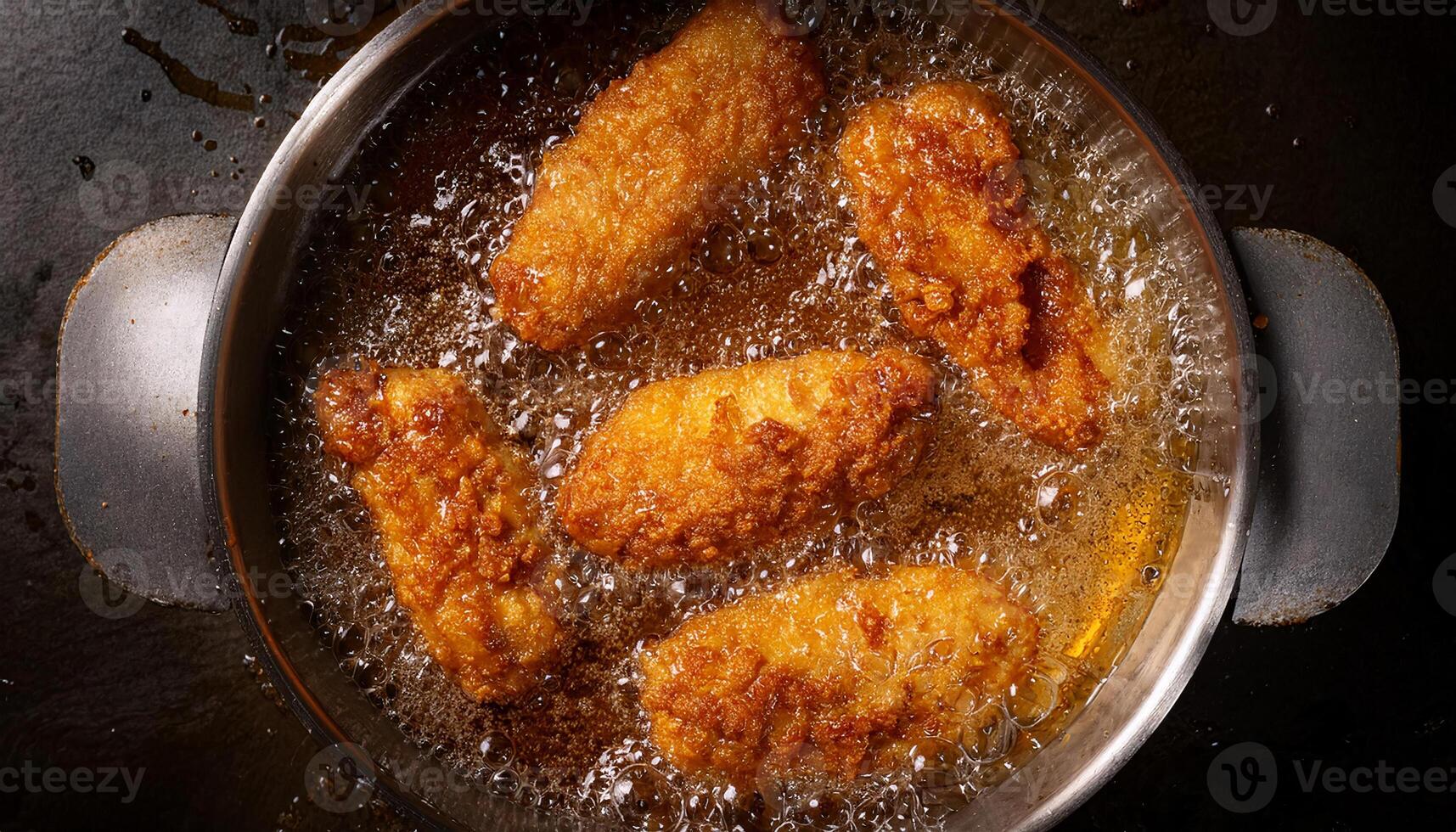 top view of chicken tenders frying in bubbling oil with a golden brown crispy crust forming photo