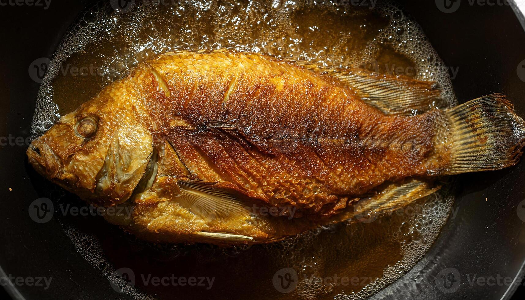 top view of a whole tilapia fish frying in hot oil with golden crispy crust and rich detailed texture photo