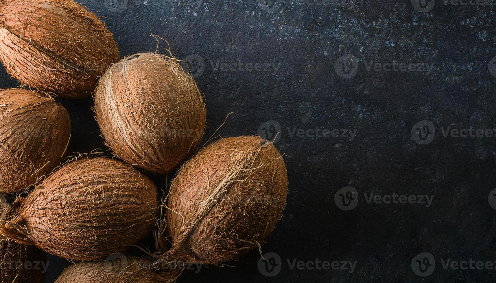 close-up top-down view of whole coconuts with textured shells against a dark background, rustic and organic tropical fruit arrangement for food and natural product concepts photo