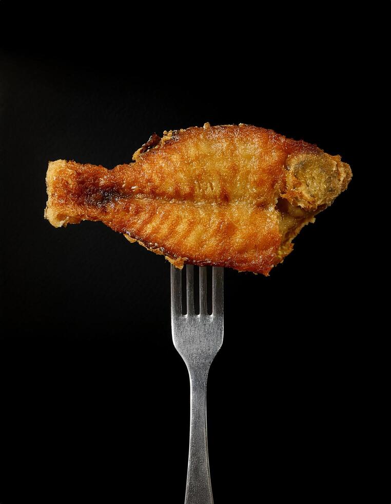 crispy deep-fried fish with golden crust on a sleek fork highlighting tender interior and rich seafood flavor against a dark background photo