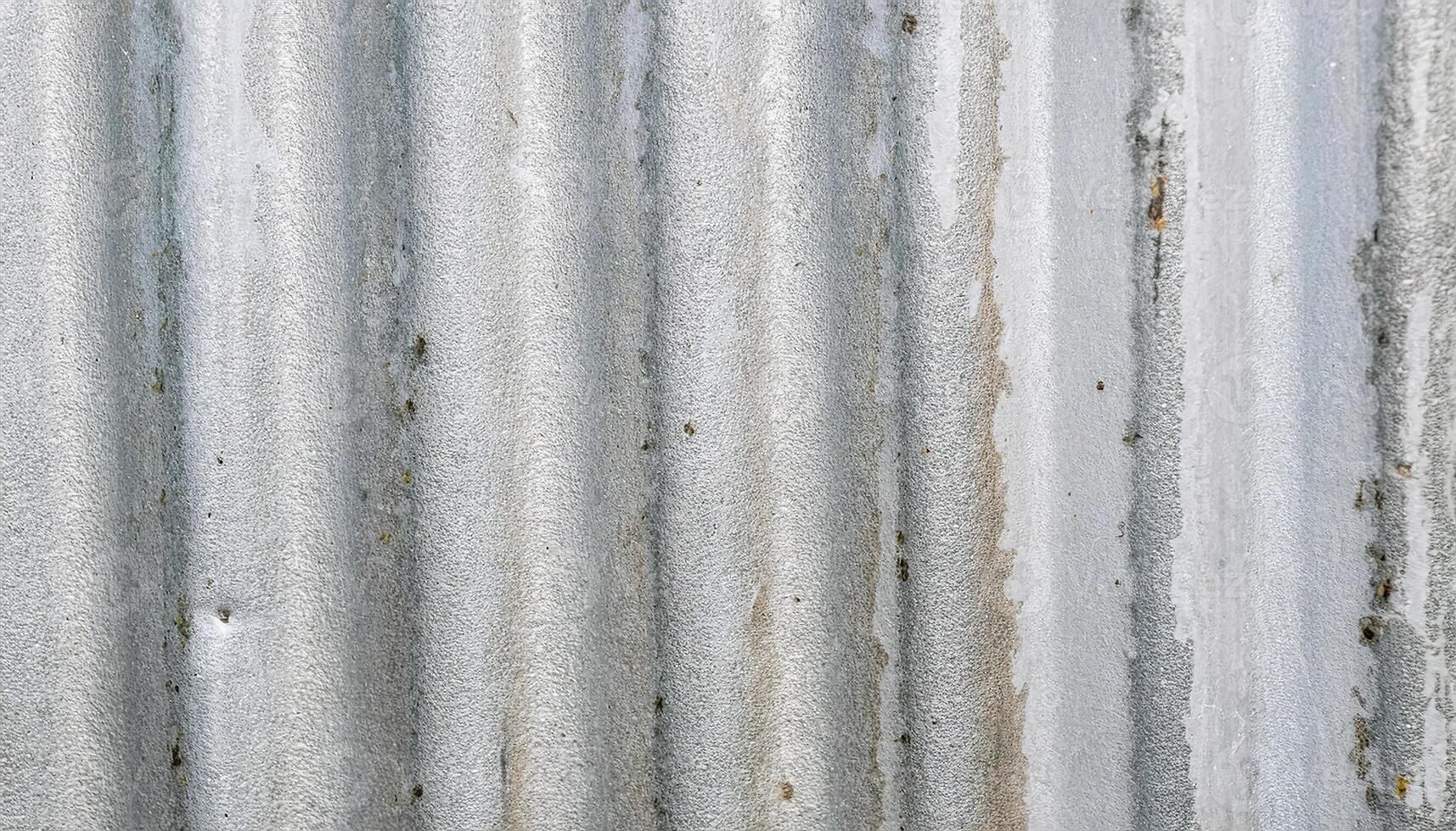 macro view of weathered zinc sheet with vertical corrugated ridges and light gray uneven textures photo