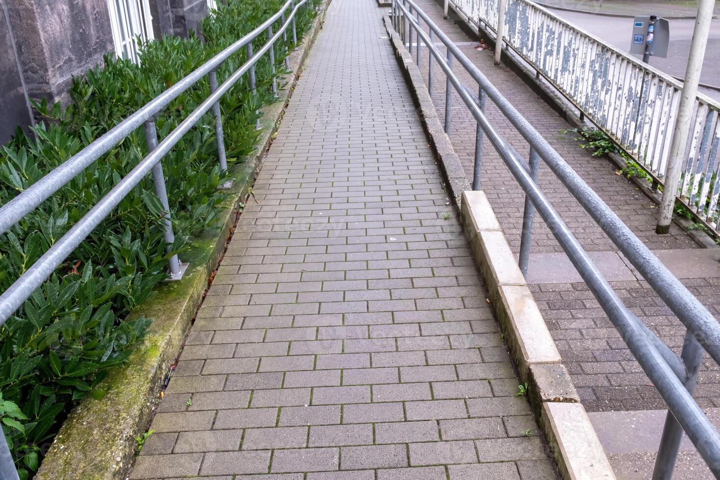 Empty ramp access for disabled people leading to grey building photo
