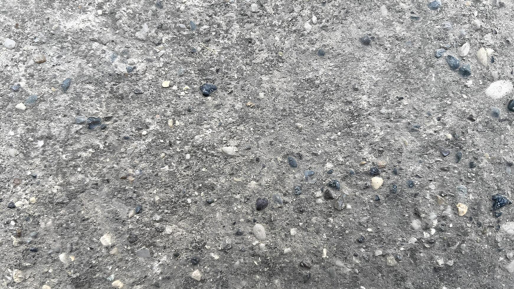 Textured surface of concrete with pebbles and small stones in daylight photo