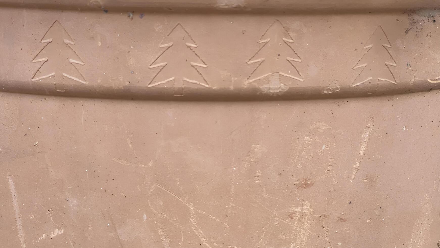 Carved tree patterns on a clay surface show traditional craftsmanship techniques photo