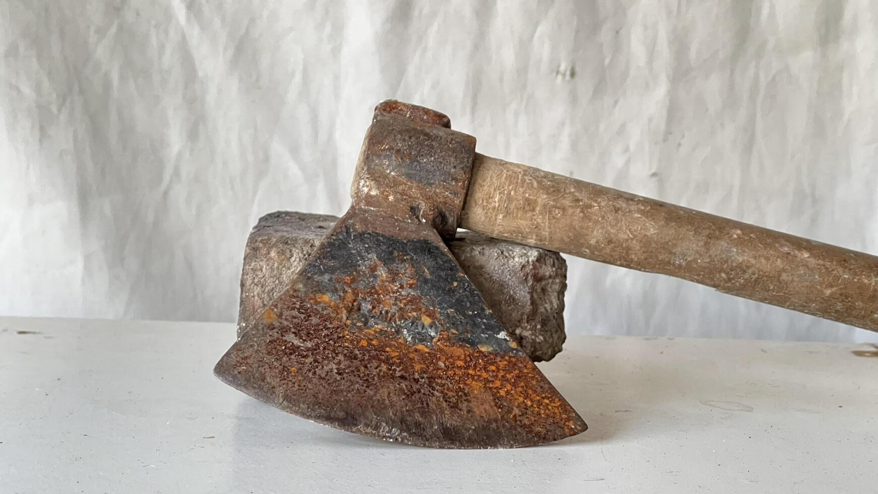Rusty axe resting on a stone block in a workshop setting photo