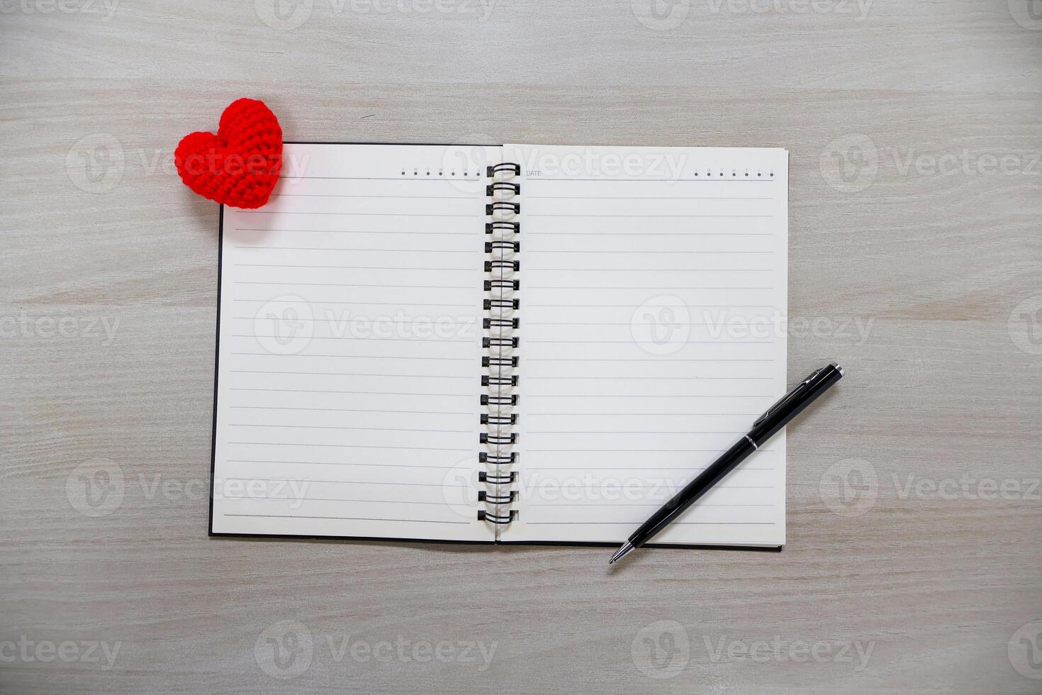 Notebook with lines and hearts and black pen on wooden table background. Valentine Day Theme photo