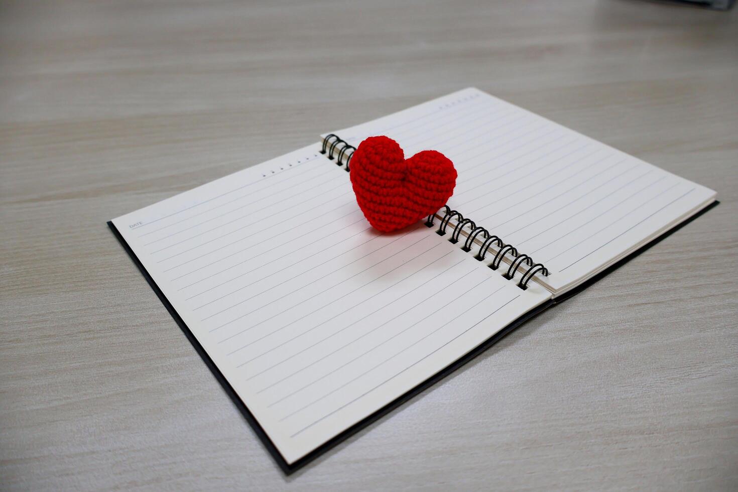 Top view. heart made of yarn on a notebook with lines page for writing. Valentine Day Theme photo