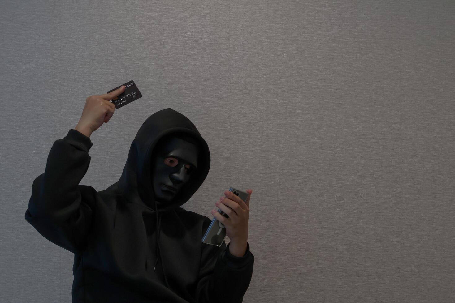 Side view Hacker, masked individuals holding phone and credit cards, call cyber scams, criminal networks stealing information from call centers. photo
