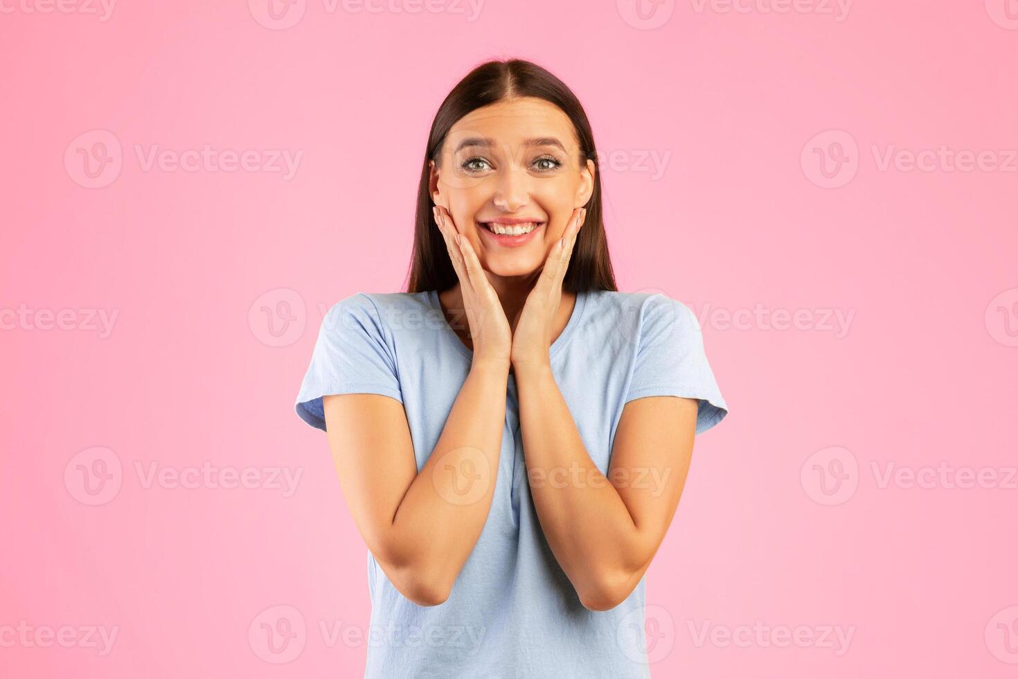 Portrait of excited lady touching cheek with joy isolated over orange studio wall, looking at camera, copyspace photo