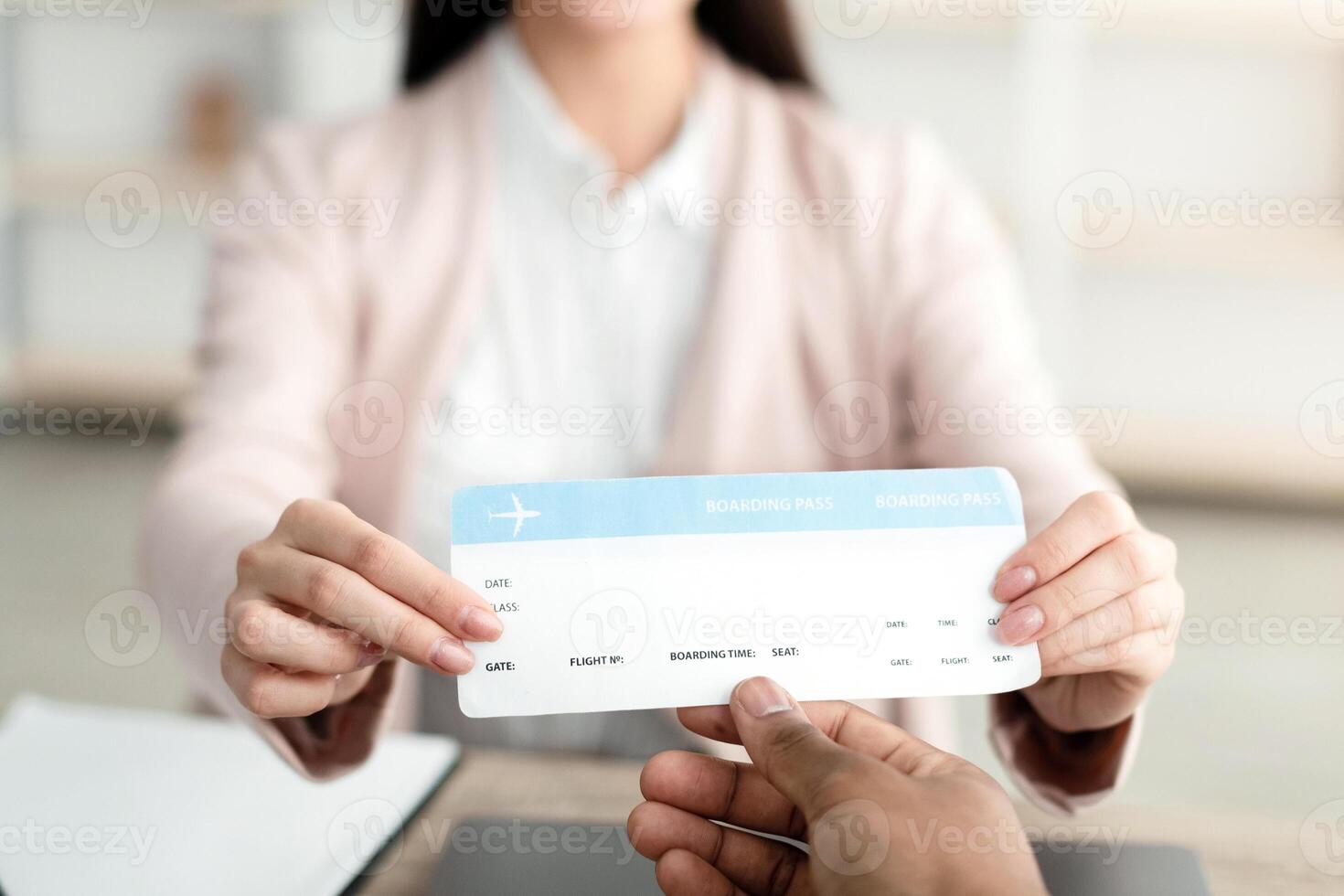 Female Travel Agent Giving Ticket To Unrecognizable Client Sitting In Tour Agency Office, Smiling To Camera. Tourism Management, Services For Travelers. Selective Focus On Boarding Pass photo
