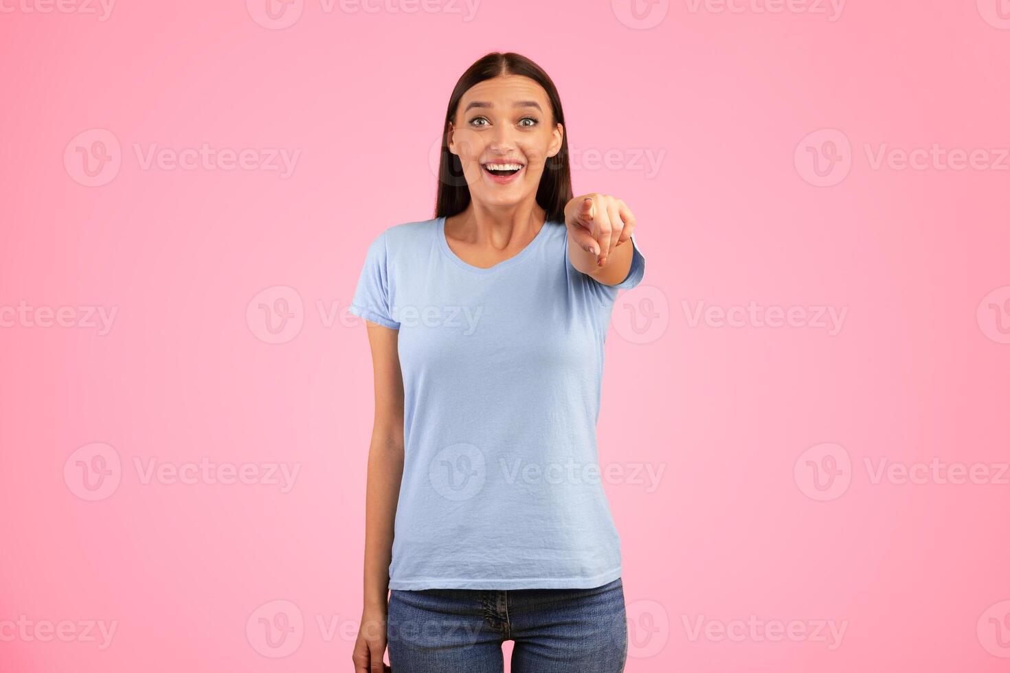 Look At You. Portrait of emotional surprised casual lady pointing finger at camera, posing isolated over yellow studio background wall. Shocked adult woman in blue shirt choosing and indicating photo