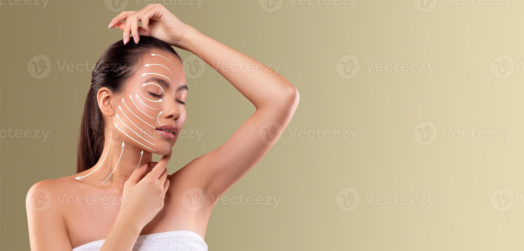 Asian woman is engaged in her beauty routine, applying skin care products to her face. She appears relaxed in a serene, isolated space, enjoying personal pampering time. photo