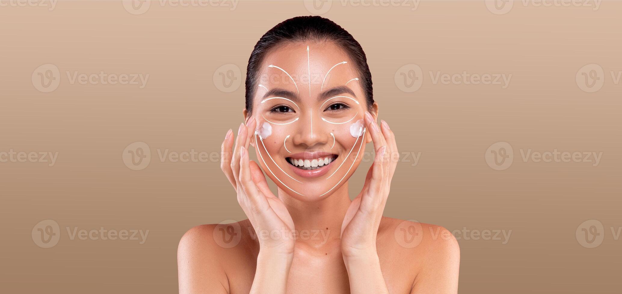 Asian woman enjoys her skincare routine, applying products while smiling in a peaceful, isolated setting. The focus is on her radiant skin and the joy of self-care amidst empty space. photo