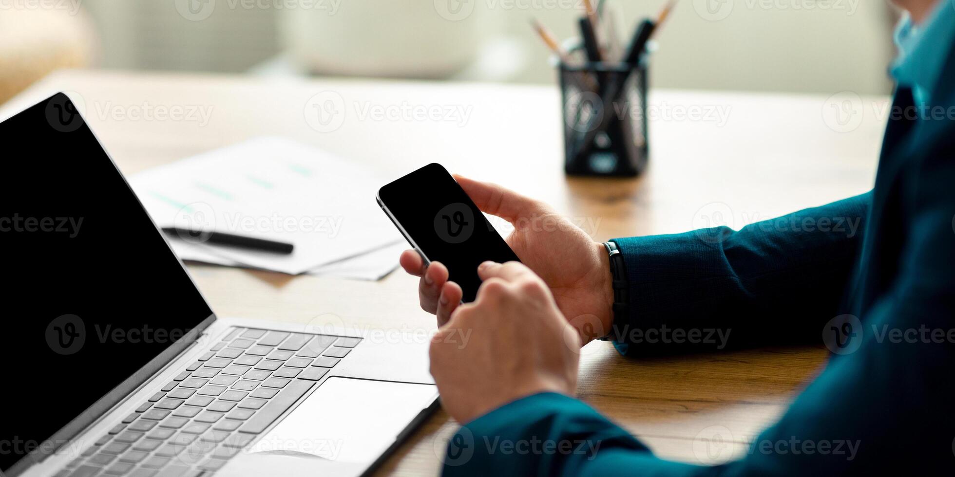 Unrecognizable guy businessman working with laptop computer and smartphone at office, mockup. Cropped view of Arab entrepreneur using modern gadgets with space for app or website design photo