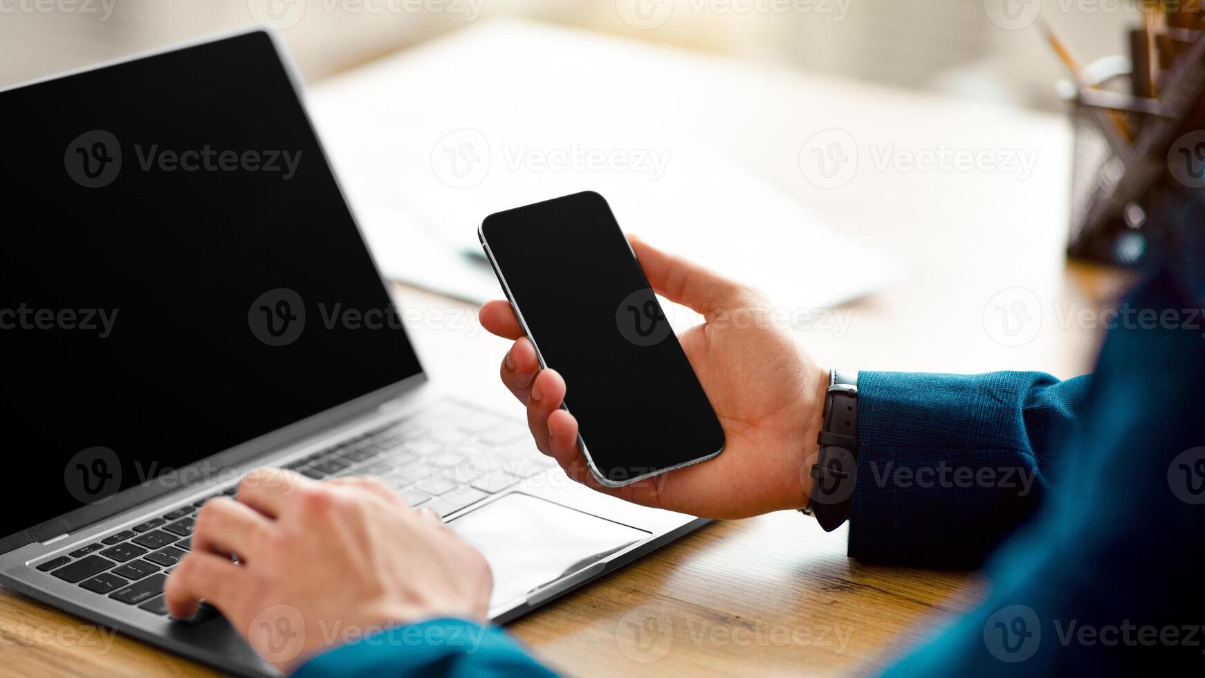 Unrecognizable Arab businessman using laptop and cellphone with mockups for website or app design, cropped. Closeup of guy freelancer working with gadgets at office, copy space photo
