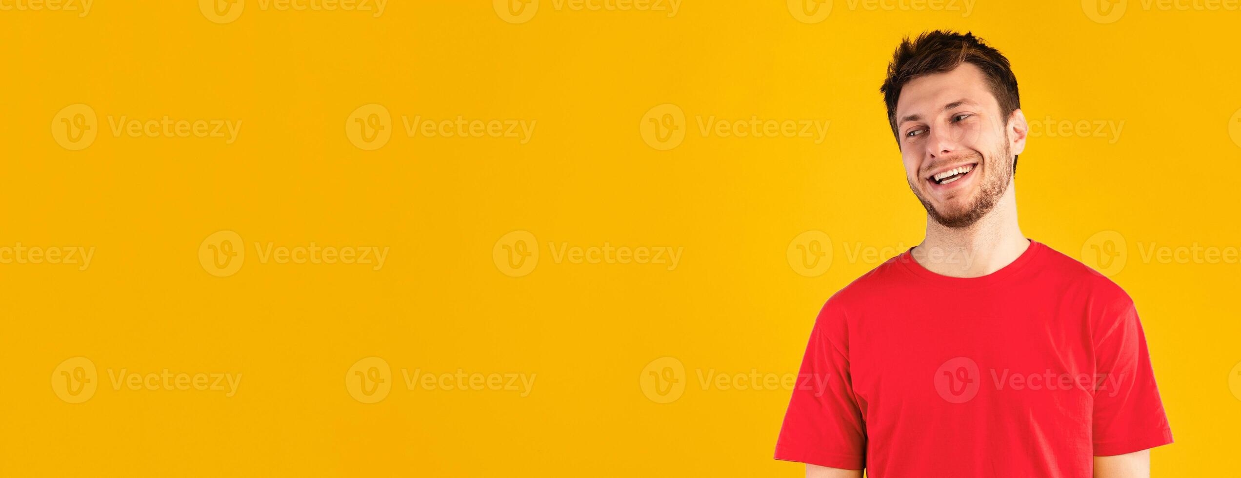 Place For Advert. Headshot portrait of smiling guy standing and looking away at copy space. Young man posing isolated over blue studio background wall. Banner for promotion, panorama. photo