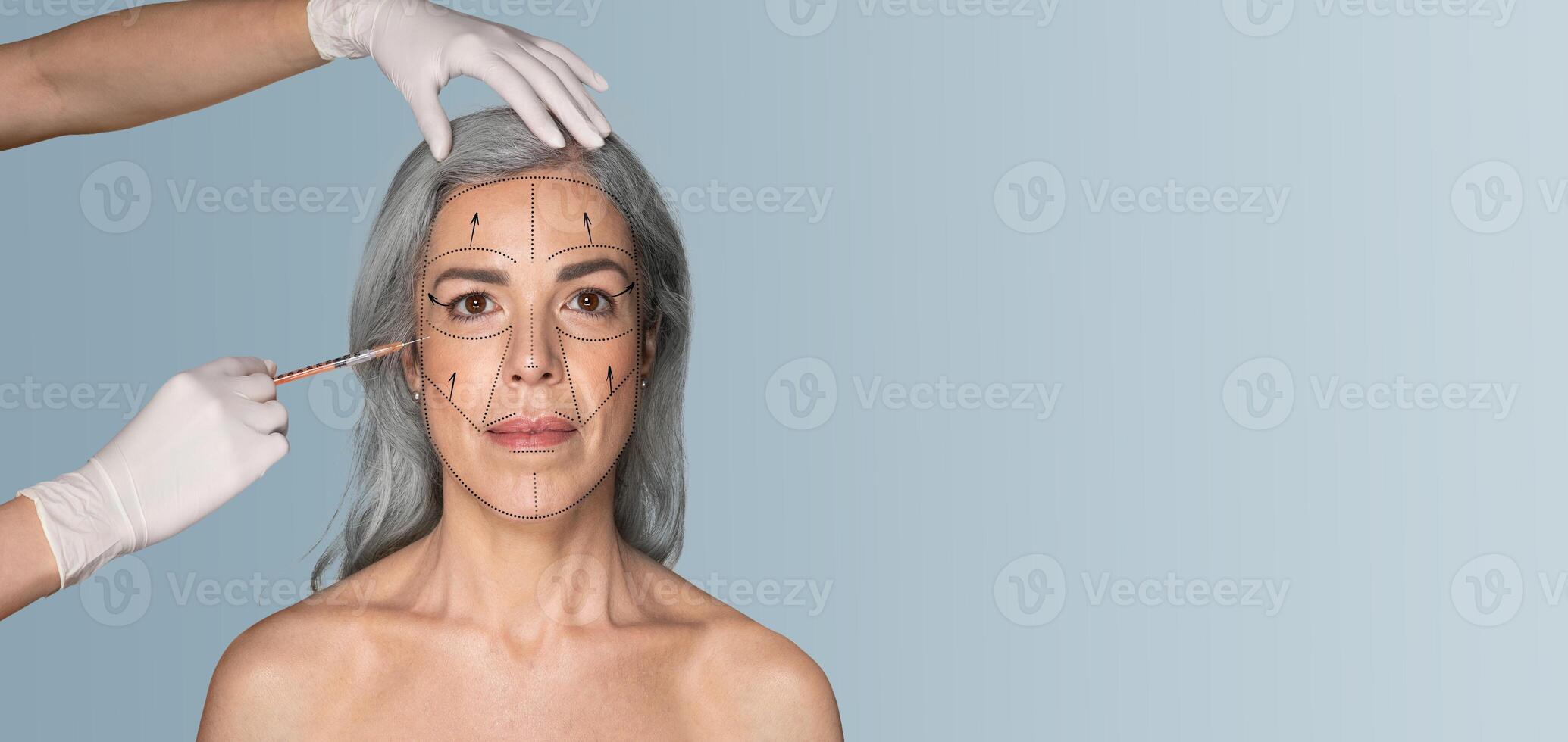 A woman with gray hair receives a skin care treatment focused on her facial features. Hands in gloves apply the treatment carefully in a clean, isolated environment, emphasizing self-care. photo
