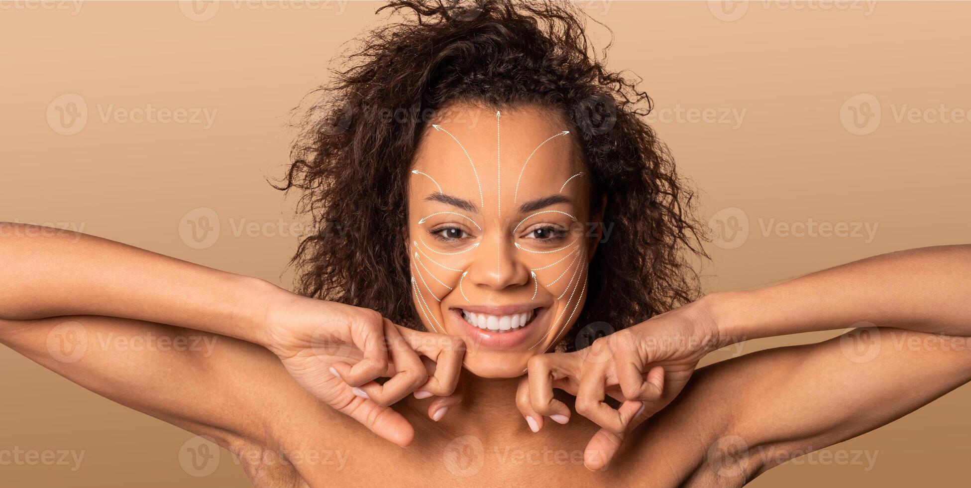 African American woman smiles while pampering herself with a skincare routine. She is in an isolated environment with a solid background, enjoying a moment of self-care and relaxation. photo